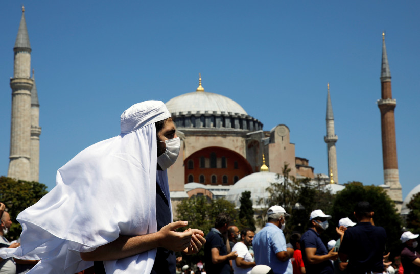 A man gestures as people wait for the beginning of Friday prayers outside Hagia Sophia Grand Mosque, for the first time after it was once again declared a mosque after 86 years, in Istanbul, Turkey, July 24, 2020 (photo credit: REUTERS/UMIT BEKTAS)