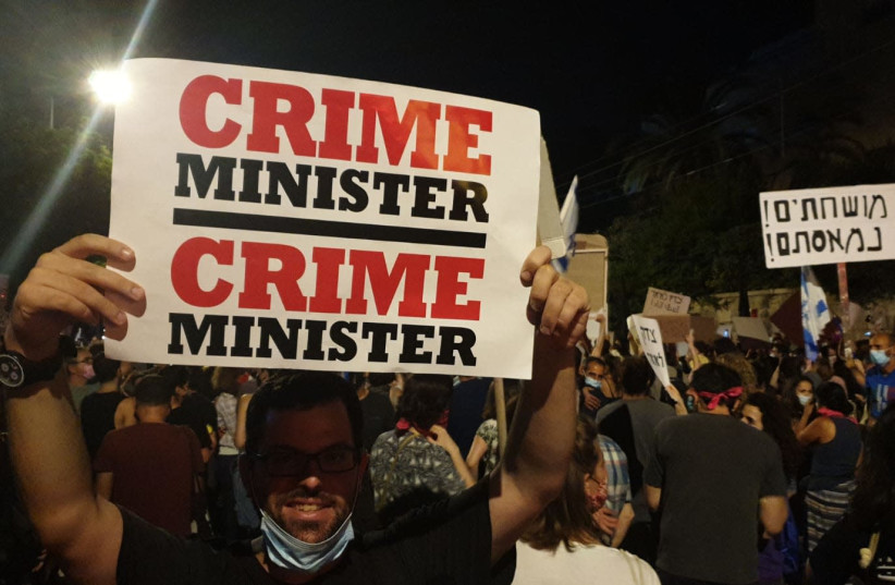 Protester holds a sign that says "crime minister" outside of the Prime Minister's Residence during a demonstration on July 25, 2020 (photo credit: TAMAR BEERI)