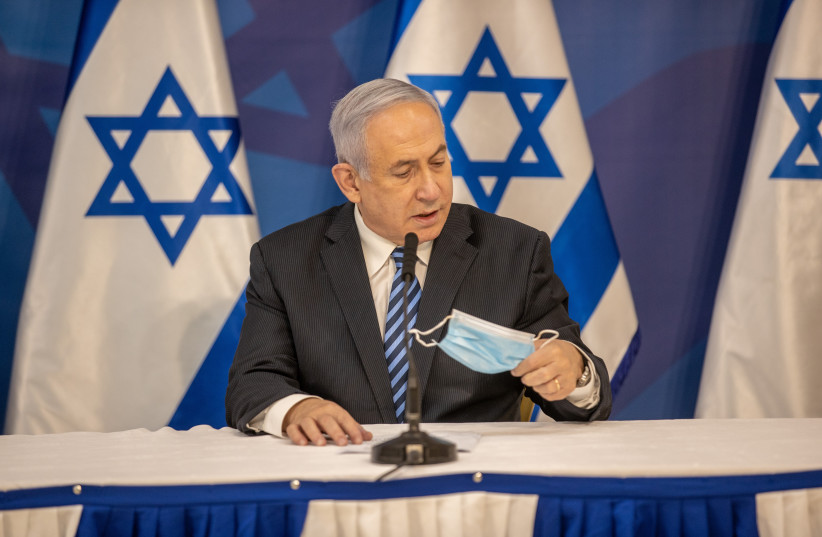 Prime Minister Benjamin Netanyahu removing his mask (photo credit: ELI DASSA)