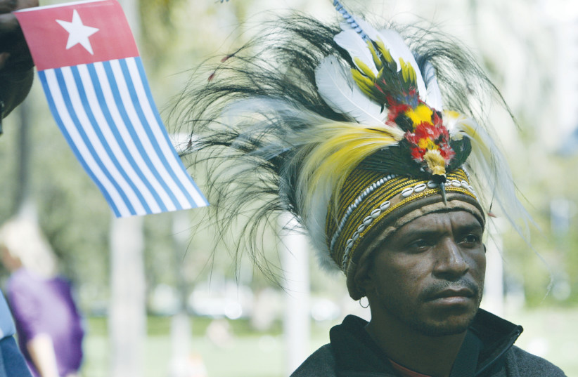 A MAN WEARING a traditional head dress stands near the Morning Star flag during a rally in Sydney, Australia, in support of West Papuans.  (photo credit: WILL BURGESS/REUTERS)