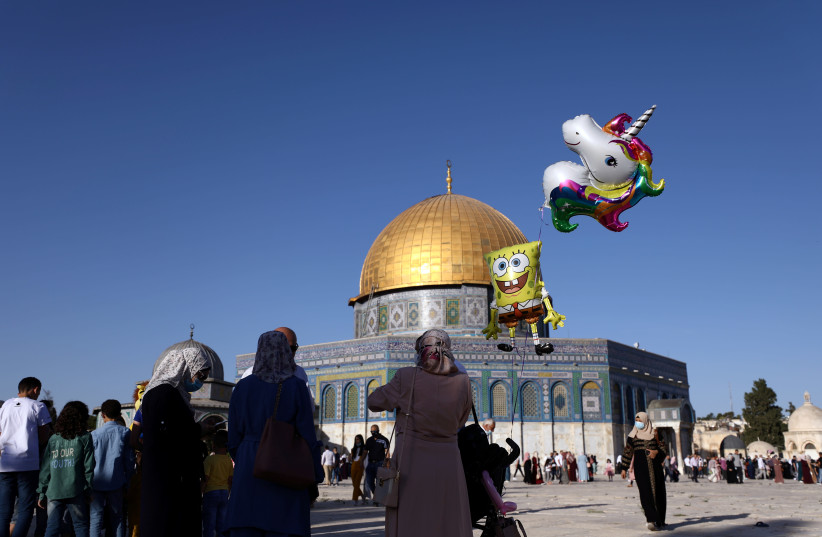 A girl poses for a photo during celebrations for the Muslim holiday of Eid al-Adha on the compound known to Muslims as Noble Sanctuary and to Jews as Temple Mount in Jerusalem's Old City amid the coronavirus disease (COVID-19) outbreak in Jerusalem, July 31, 2020 (photo credit: REUTERS/AMMAR AWAD)