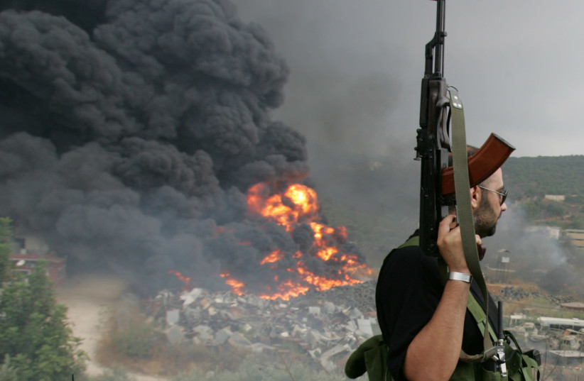 A Lebanese Hezbollah guerrilla looks at a fire rising from a burning object in a Beirut suburb, Lebanon July 17, 2006. (photo credit: REUTERS/ISSAM KOBEISI/FILE PHOTO)