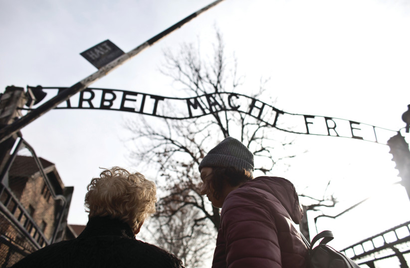 JONA LAKS, survivor of Dr. Josef Mengele’s twins experiments, and granddaughter Lee Aldar pass under the notorious Auschwitz death camp gate in January. (photo credit: NIR ELIAS / REUTERS)