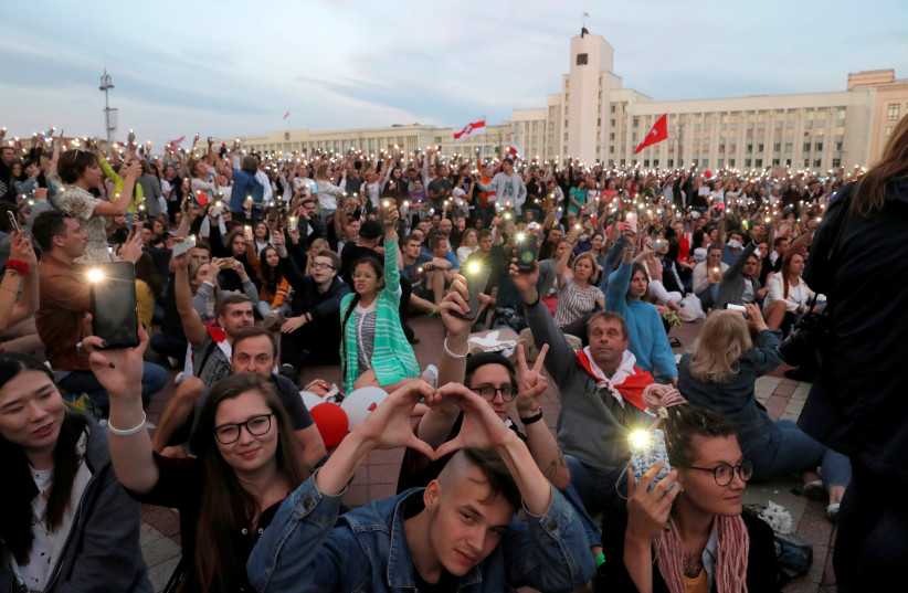 Demonstrators hold their phones with flashlights on during an opposition demonstration to protest against police violence and to reject the presidential election results near the Government House in Independence Square in Minsk, Belarus August 14, 2020. (photo credit: REUTERS/VASILY FEDOSENKO)