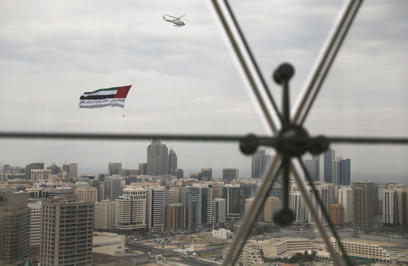 A helicopter flies over the downtown skyline, amid the coronavirus disease (COVID-19) outbreak, as seen from the Cleveland Clinic hospital in Abu Dhabi, United Arab Emirates, April 20, 2020. (photo credit: REUTERS/CHRISTOPHER PIKE)