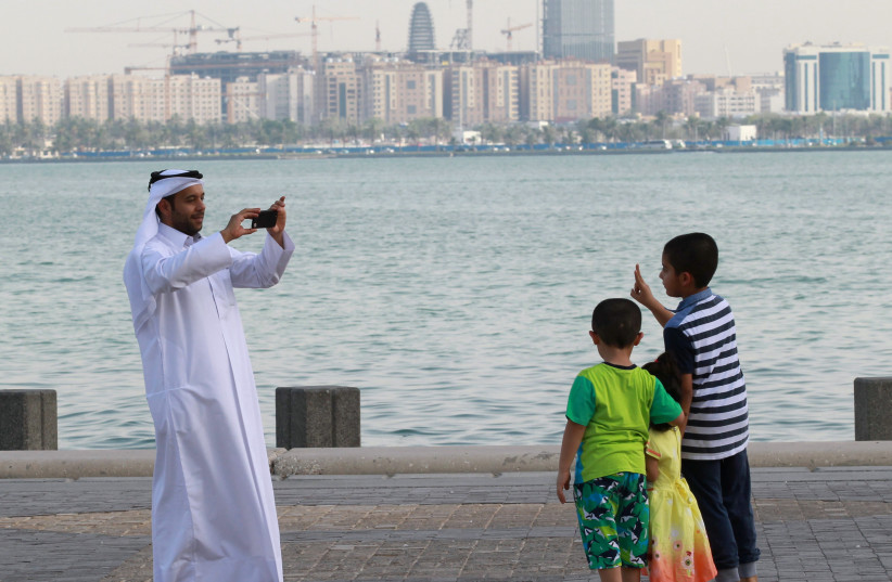 A man takes a picture of his children on the corniche in Doha, Qatar, June 6, 2017. (photo credit: NASEEM ZEITOON/REUTERS)