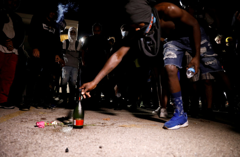 A bottle of alcohol and flowers are left in tribute to the victims of a shooting during Tuesday night's protests, at the site of the incident, during a protest following the police shooting of Jacob Blake, a Black man, in Kenosha, Wisconsin, U.S. August 26, 2020. (photo credit: BRENDAN MCDERMID/REUTERS)