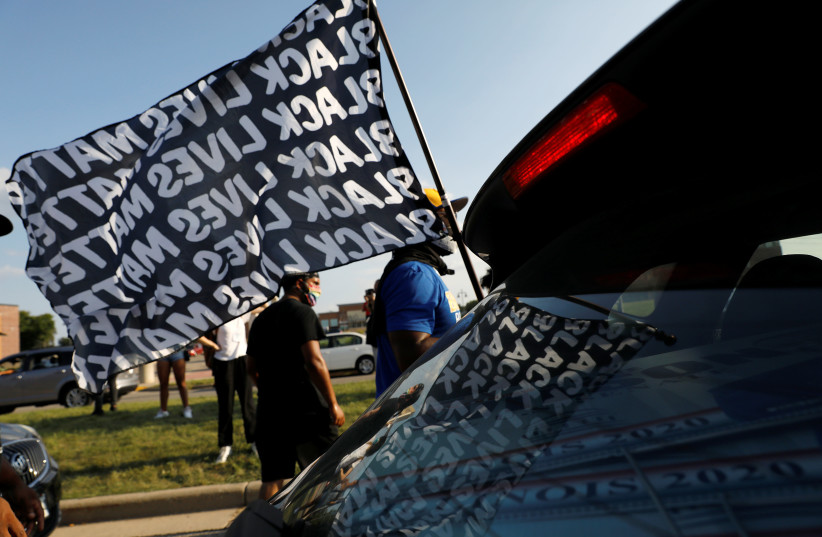 A man holds a flag with the words Black Lives Matter during a protest following the police shooting of Jacob Blake, a Black man, in Kenosha, Wisconsin, US, August 27, 2020. (photo credit: REUTERS)