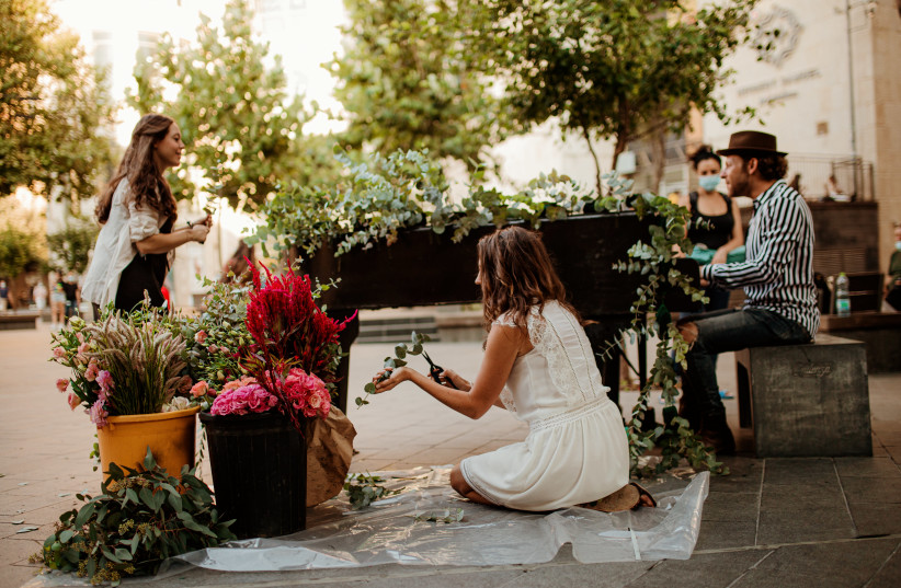 Florists Mookie Cohen and Sara Winter create a floral installation in downtown Jerusalem while Yitzchok Meir Malek plays piano for cheerful passers-by (photo credit: TZIPORA LIFCHITZ PHOTOGRAPHY)