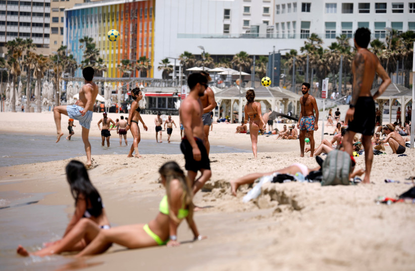 People visit a beach along the coast of the Mediterranean Sea during a heatwave in Israel as restrictions following the coronavirus disease (COVID-19) ease around the country, in Tel Aviv, Israel, May 17, 2020 (photo credit: REUTERS/AMIR COHEN)