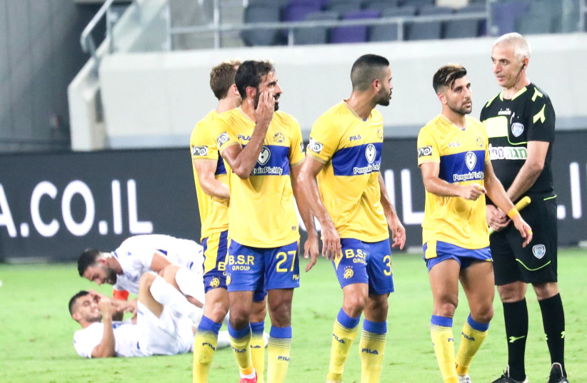 MACCABI TEL AVIV players react in dismay while Maccabi Petah Tikva players celebrate in the background after scoring the game-winning goal in their surprising 2-1 victory over the defending champs in Sunday night’s season opener at Bloomfield Stadium. (photo credit: DANNY MARON)