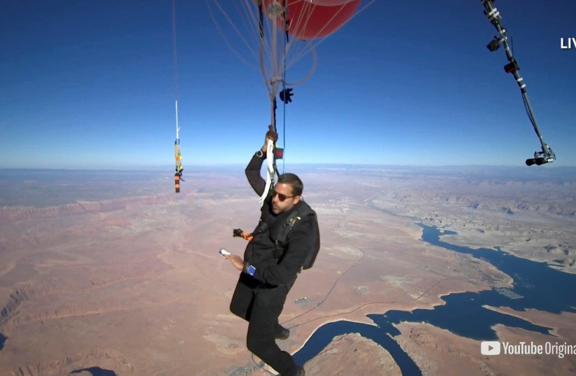 Extreme performer David Blaine hangs with a parachute under a cluster of balloons during a stunt to fly thousands of feet into the air in a still image from video taken over Page, Arizona, U.S. September 2, 2020 (photo credit: DAVID BLAINE/HANDOUT VIA REUTERS)