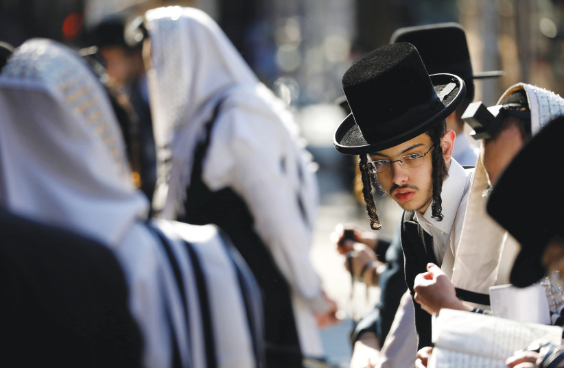 HASSIDIC MEN gather for morning prayer outside of a synagogue in Brooklyn. The proliferation of massive numbers of smaller, socially distanced, outdoor backyard minyanim should not be feared but welcomed. (photo credit: ANDREW KELLY / REUTERS)