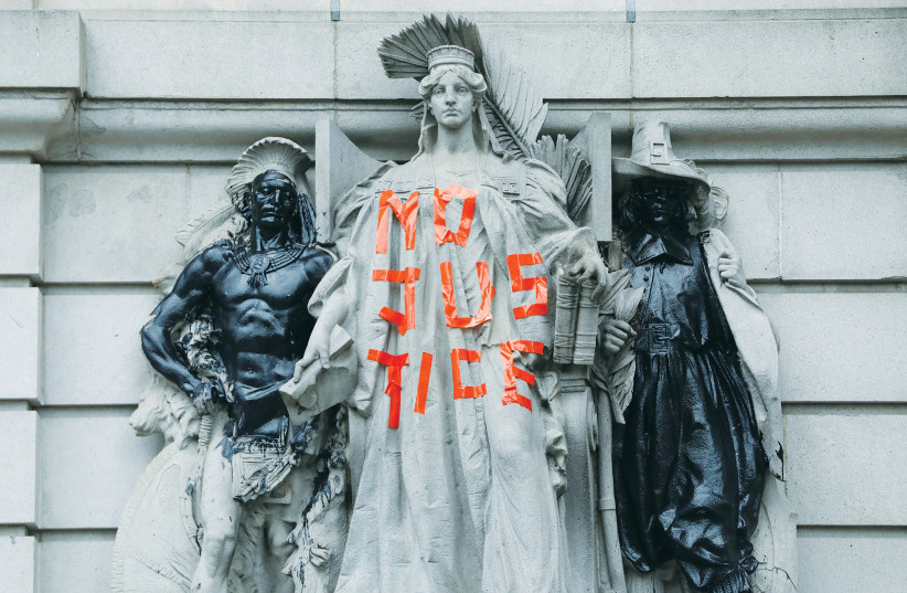 Vandalized statues are seen outside the Surrogate’s Court, across from the ‘City Hall Autonomous Zone’ supporting Black Lives Matter, in Manhattan in June. (photo credit: ANDREW KELLY / REUTERS)