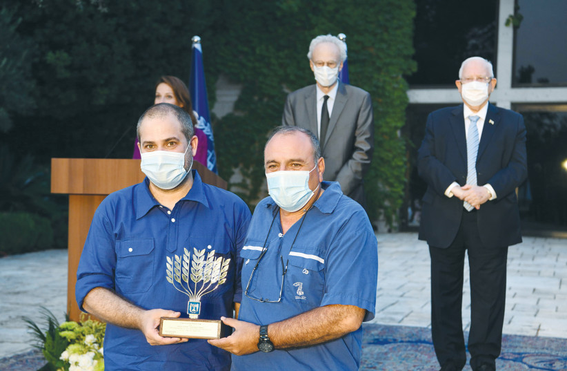 ILAN GAZIT and Nissim Shalom of The Council of Youth Movements and the Pioneer Federation with their prize trophy as President Reuven Rivlin and Baruch Levy, president of the National Council for Volunteerism, stand in the background in the garden of the President’s Residence. (photo credit: AMOS BEN GERSHOM, GPO)