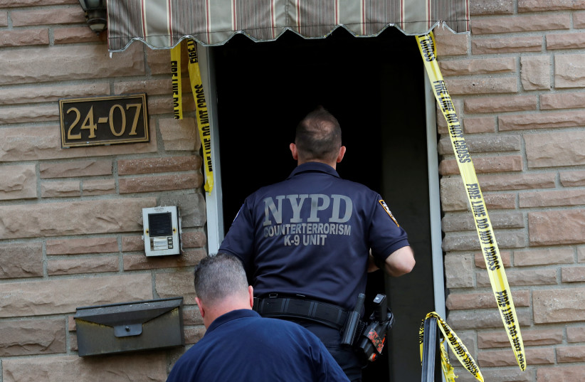 A New York Police Department (NYPD) Counterterrorism K-9 Unit officer enters a house, where police say bomb-making materials were found following a fire in the house, in the Queens borough of New York City, New York, US, September 16, 2020.  (photo credit: REUTERS)