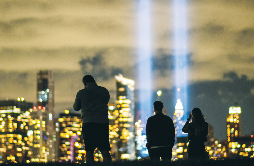 PEOPLE LOOK at ‘The Tribute in Light’ installation in Jersey City on the 19th anniversary of the 9/11 attacks. (photo credit: REUTERS)