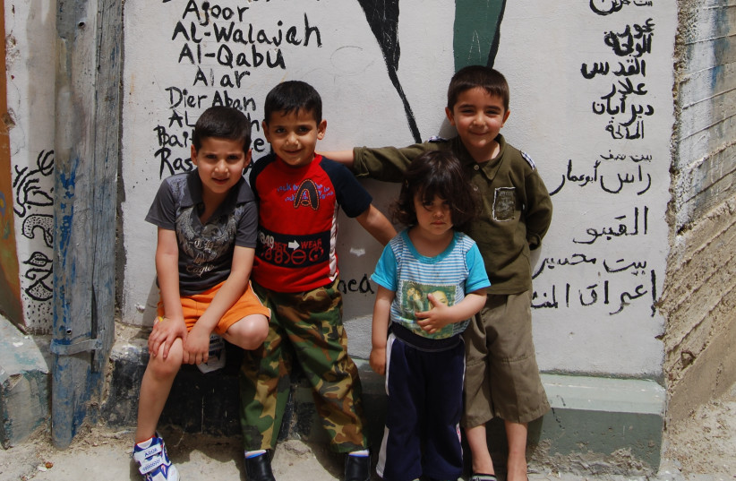 Palestinian children pose in front of a map of Israel covered with the Palestinian flag, vowing to return to their families’ former homes (photo credit: DAVID BEDEIN)