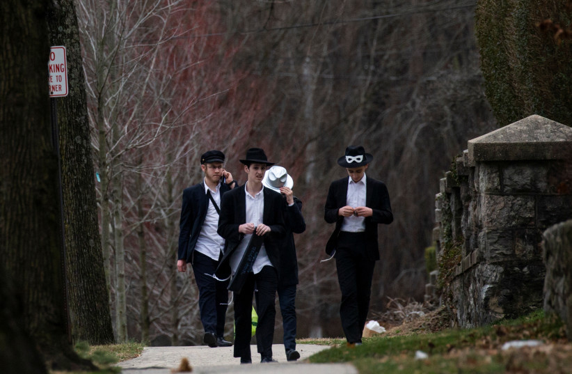 People walk on a street less than a mile away from Young Israel orthodox synagogue in New Rochelle, New York, U.S., March 10, 2020. (photo credit: EDUARDO MUNOZ / REUTERS)