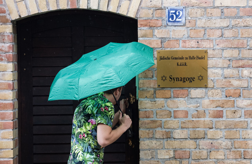 An onlooker examines the bullet marks that were still visible on the door to the synagogue in Halle, Germany, July 20, 2020.  (photo credit: JENS SCHLUETER/AFP VIA GETTY IMAGES)