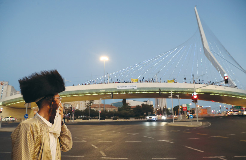 AN ULTRA-ORTHODOX man watches protesters march across Jerusalem’s ‘Bridge of Strings’ in August.  (credit: REUTERS)