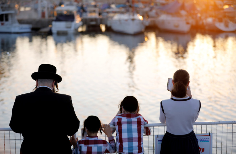 Jewish worshippers perform the Tashlich ceremony, whereby Jews symbolically cast away their sins ahead of Yom Kippur, the Jewish Day of Atonement, as Israel is set to tighten its second nationwide coronavirus disease (COVID-19) lockdown amid a rise in infections season in Ashdod, Israel September 24 (photo credit: REUTERS/AMIR COHEN)