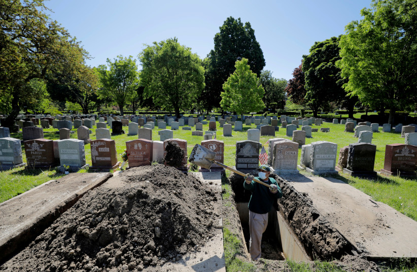 Roberto Arias prepares a grave for burial at Woodlawn Cemetery during the coronavirus disease (COVID-19) outbreak in Everett, Massachusetts, US, May 27, 2020. (photo credit: BRIAN SNYDER/REUTERS)