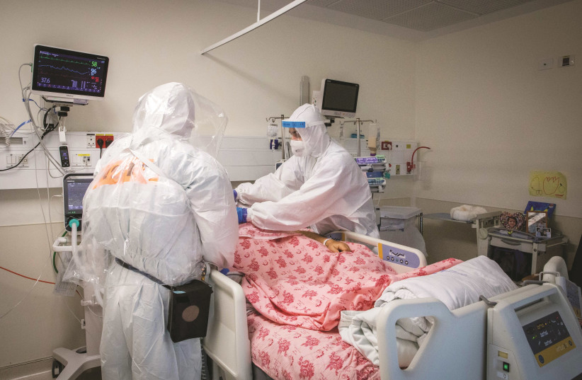 SHAARE ZEDEK hospital team members assist a corona ward patient, in Jerusalem on September 23. (photo credit: NATI SHOHAT/FLASH90)