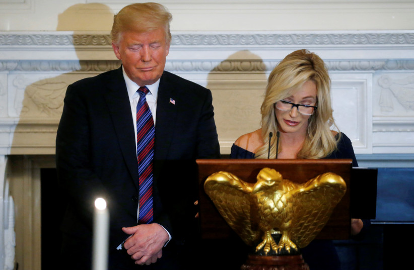 U.S. President Donald Trump closes his eyes as Pastor Paula White leads a prayer at a dinner hosted by the Trumps to honor evangelical leadership in the State Dining Room at the White House in Washington, D.C., U.S. August 27, 2018 (photo credit: REUTERS/LEAH MILLIS)