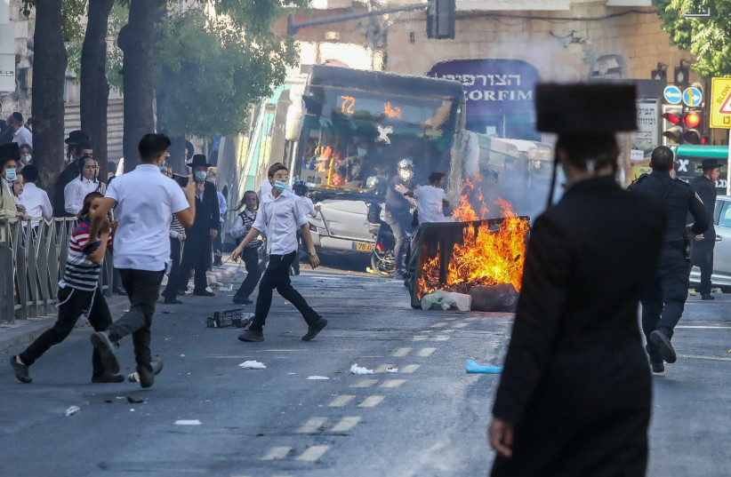 Haredim are seen rioting in Jerusalem, with a garbage can lit ablaze to block the street. (credit: MARC ISRAEL SELLEM/THE JERUSALEM POST)