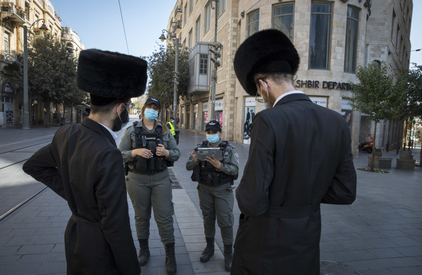 Israeli border police officers check citizens on Jaffa Street in downtown Jerusalem on October 7, 2020, during a nationwide lockdown to prevent the spread of COVID-19. (photo credit: NATI SHOHAT/FLASH90)