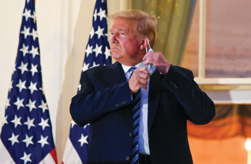US PRESIDENT Donald Trump pulls off his protective face mask after returning to the White House last week, after being hospitalized for the coronavirus. October 9,  2020. (photo credit: REUTERS)