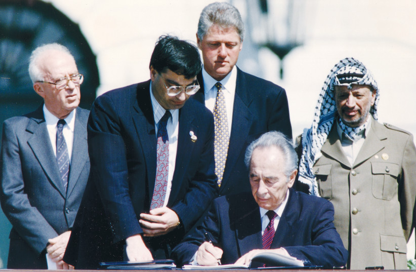 THEN-foreign minister Shimon Peres (sitting 2nd right) signs the Israeli-PLO peace accord as then-PLO chairman Yasser Arafat, then-prime minister Yitzhak Rabin and then-US president Bill Clinton stand behind him during a ceremony, at the White House in Washington, September 13, 1993. (photo credit: REUTERS)