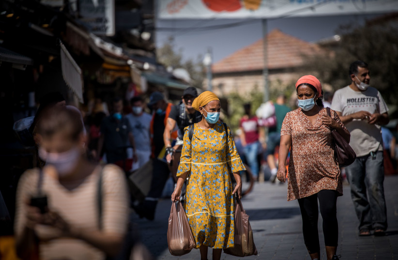 People wearing face masks shop at the Mahane Yehuda Market in Jerusalem on October 7, 2020, during a nationwide lockdown to prevent the spread of COVID-19 (photo credit: YONATHAN SINDEL/FLASH90)
