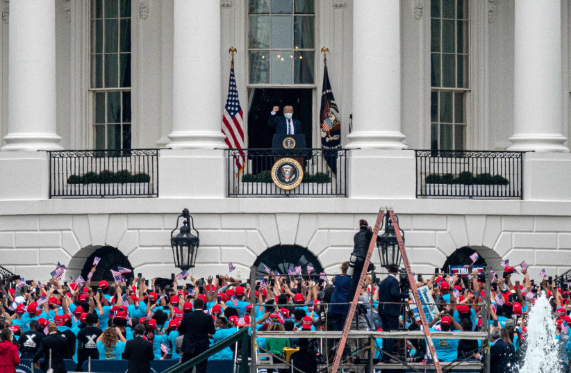 US President Donald Trump gestures from a White House balcony towards supporters gathered on the South Lawn for a campaign rally in Washington, US, October 10, 2020. (photo credit: REUTERS/KEN CEDENO)