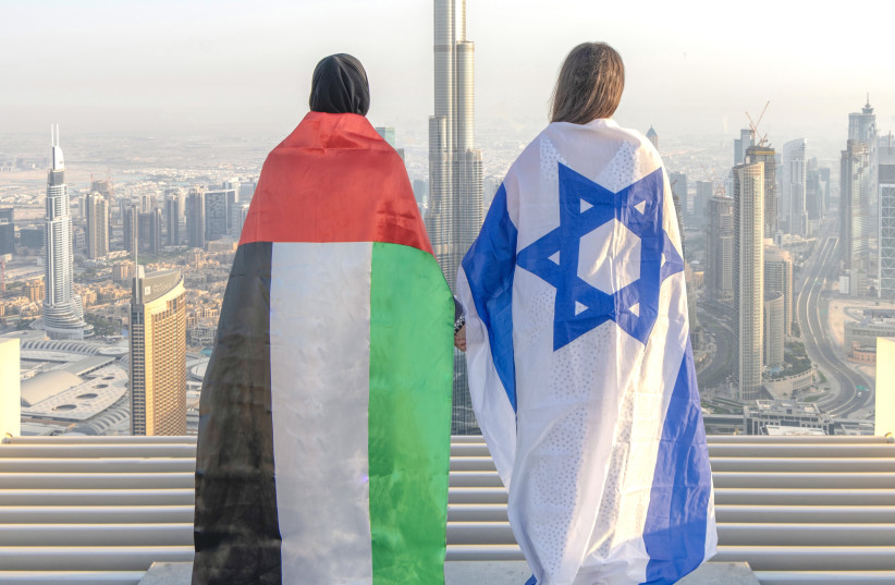 Emirati Norah al-Awadhi and friend, Israeli Ronny Gonen, stand facing the Burj Khalifa, the world’s tallest building, draped in their countries' flags (photo credit: ABDULLAH SAMEH HOUSSNY/@DUBAI.UAE.DXB)