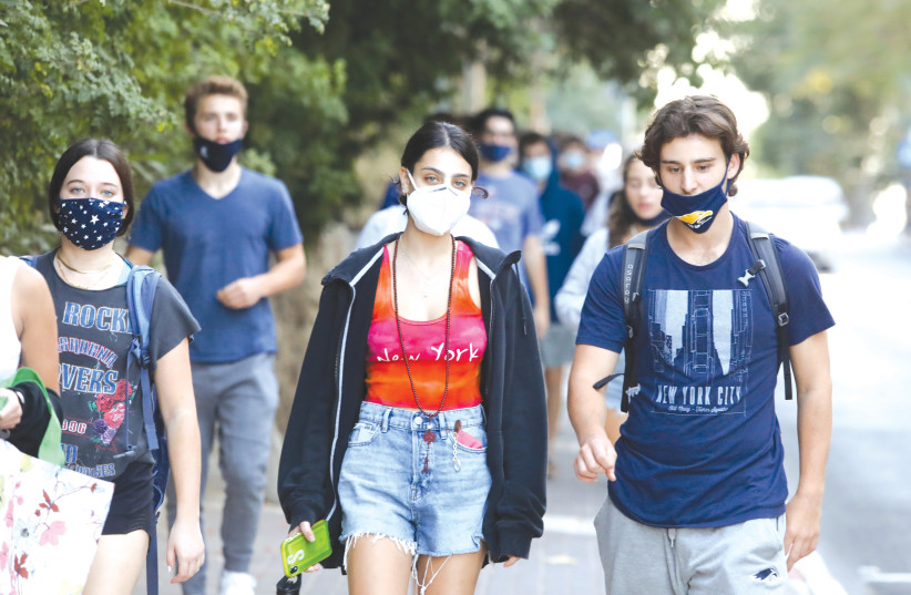 Youths, some wearing masks properly and some not, walk on a Jerusalem sidewalk, October 2020 (photo credit: MARC ISRAEL SELLEM/THE JERUSALEM POST)