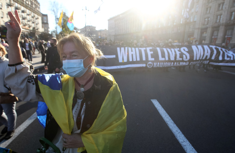A woman wearing a Ukrainian flag performs an ultranationalist gesture while marching at an event honoring collaborators with Nazi Germany in Kyiv, Ukraine on Oct. 14, 2020. (photo credit: STR/NURPHOTO VIA GETTY IMAGES)