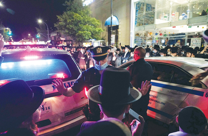 NYPD officers speak with ultra-Orthodox Jews as they protest in the Borough Park neighborhood of Brooklyn, on October 7.  (credit: REUTERS)