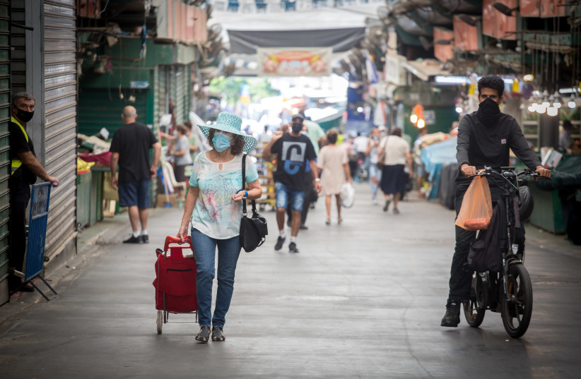 Israelis wear protective face masks as they walk through the haTikva market in Tel Aviv, during a nationwide lockdown. October 05, 2020. (photo credit: MIRIAM ALSTER/FLASH90)