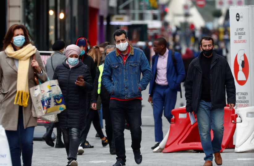 People wearing protective masks walk in a shopping street amid the coronavirus disease outbreak in Brussels (photo credit: REUTERS/FRANCOIS LENOIR)