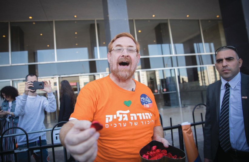 Yehuda Glick hands out heart tokens outside the Likud polling station, February 2019.  (photo credit: YONATAN SINDEL/FLASH90)