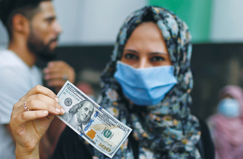 UNE FEMME montre un billet de 100 $ qu'elle a reçu comme aide du Qatar, lors d'un confinement au milieu de l'épidémie de coronavirus dans la ville de Gaza en septembre. (crédit photo : MOHAMMED SALEM/ REUTERS)
