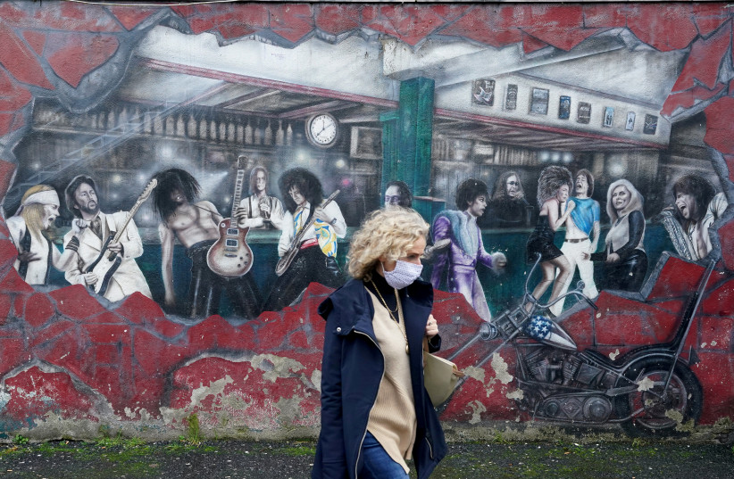 A woman walks past a wall mural during the resurging coronavirus outbreak in Galway, Ireland, October 20, 2020. (photo credit: REUTERS/CLODAGH KILCOYNE)