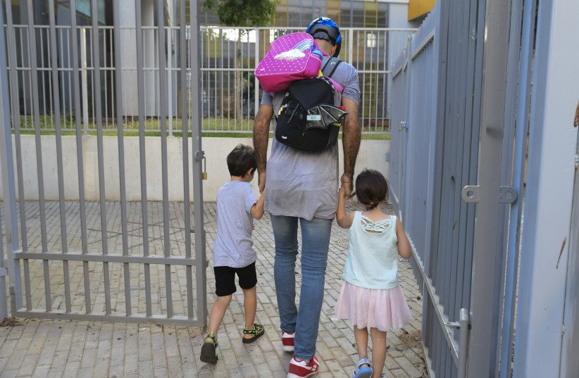Parents accompany their children to the kindergarten in Tel Aviv as they return to kindergarden on October18, 2020 after being shut down during a national lockdown in a means to prevent the spread of the Coronavirus.  (photo credit: AVSHALOM SASSONI/FLASH90)