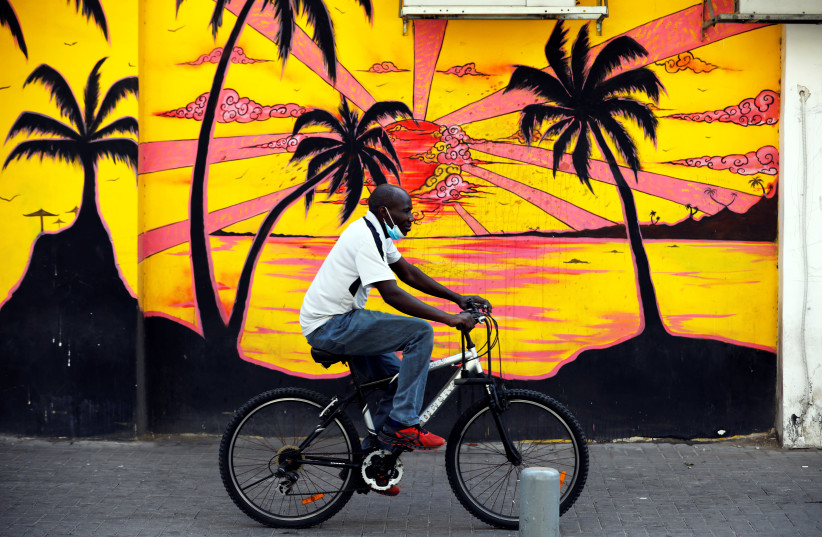 An African migrant rides his bicycle in a street in south Tel Aviv, Israel October, 25, 2020. (photo credit: AMIR COHEN/REUTERS)