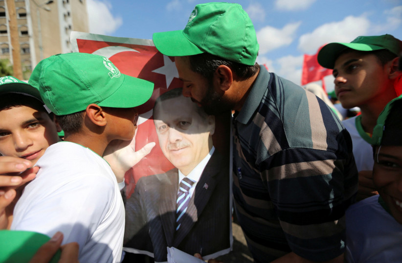Palestinian Hamas supporters kiss a poster of Turkish President Tayyip Erdogan during a Hamas rally in support of Erdogan's government against a coup attempt (photo credit: IBRAHEEM ABU MUSTAFA / REUTERS)