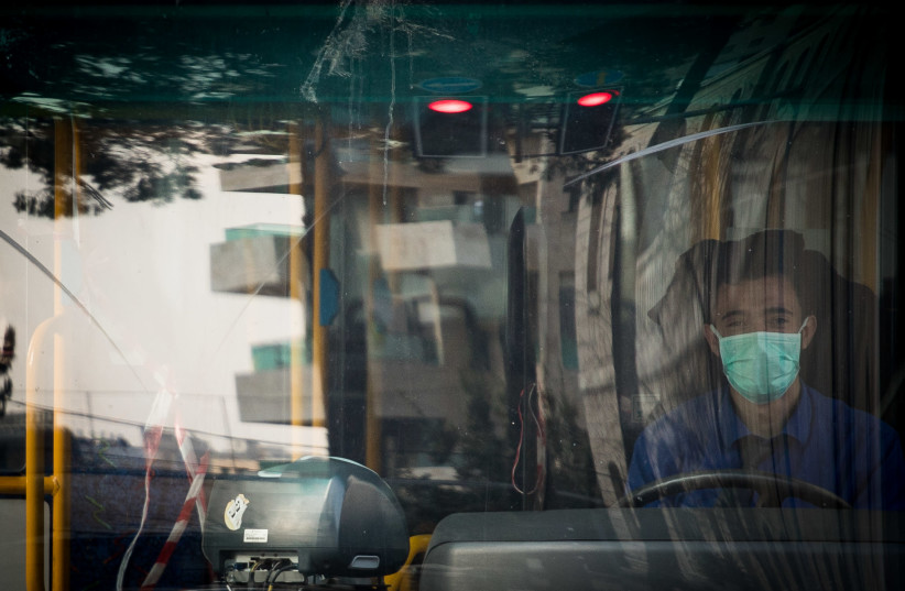 A bus driver sits in a bus and wears a face mask for fear of the coronavirus in downtown Jerusalem, March 16, 2020. (photo credit: YONATAN SINDEL/FLASH 90)