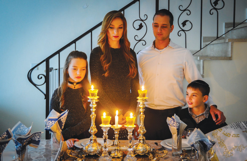 A JEWISH FAMILY gathers after lighting Shabbat candles. (credit: ILLUSTRATIVE PHOTO/MENDY HECHTMAN/FLASH90)
