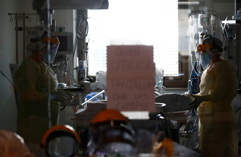 Medical workers take care of a patient infected with COVID-19 at the intensive care unit (ICU) of Ramon y Cajal hospital amid the coronavirus disease (COVID-19) outbreak in Madrid, Spain October 30, 2020. (photo credit: REUTERS)